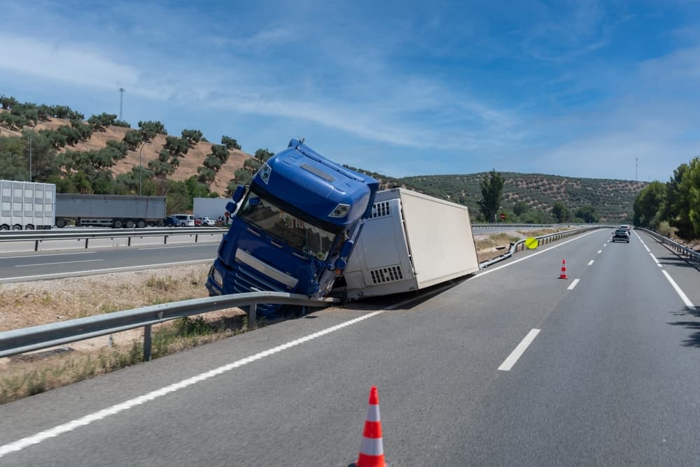 A refrigerated semi-trailer truck overturned in the highway median near the exit.