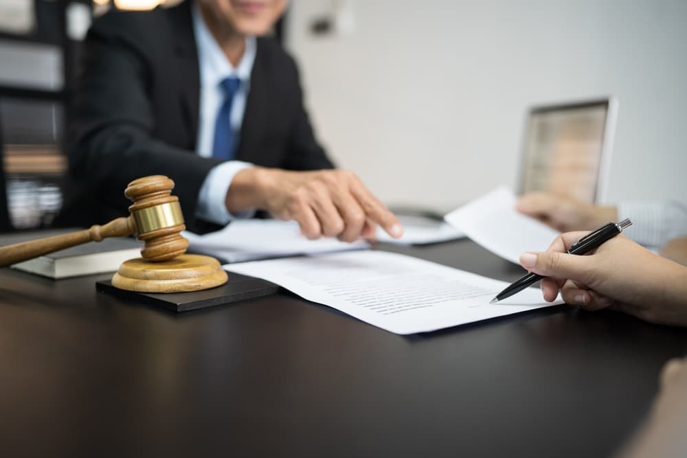 The legal counsel presents a signed contract to the client, symbolizing justice and the law, alongside a gavel, reflecting the lawyer’s commitment to upholding legal principles.