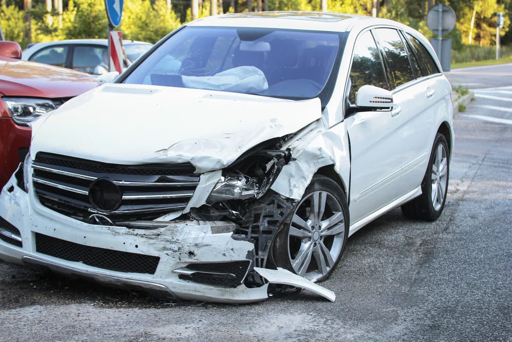 The front of a car is damaged in a road crash accident.