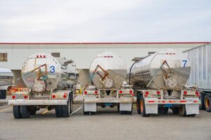 A row of three gleaming metal tanker trucks designed for fuel transportation.