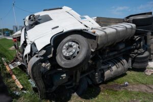 The truck is overturned on its side following a car accident on the highway.