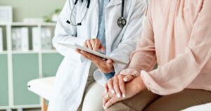 A doctor and patient use a tablet for consultation in a clinic, utilizing digital technology for healthcare services and telehealth assistance in a hospital.