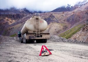 The image of a fuel truck broken down in a mountainous area with an emergency sign placed behind it, as described.